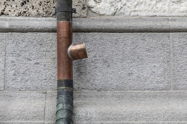 Copper plumbing pipe with T-junction on stone wall