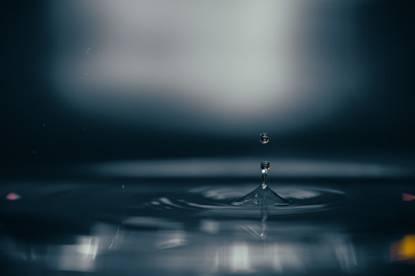 Water droplet falling into calm blue water